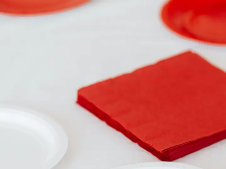 Servilletas rojas apiladas junto a platos blancos